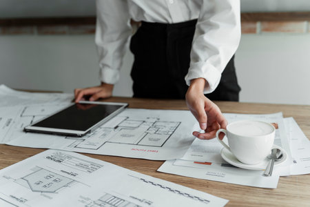 Cropped image of woman's hand grab the cup of hot coffee on the table while working.