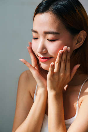 Close up portrait - Young asian woman cleaning her face with lotion or water.の写真素材