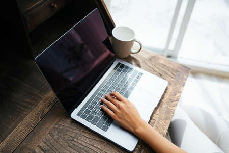 Hands of freelancer working on laptop computer on wooden desk.の写真素材