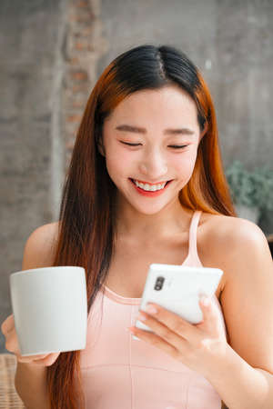 Young asian woman enjoy having coffee and watching something funny on social media.の写真素材