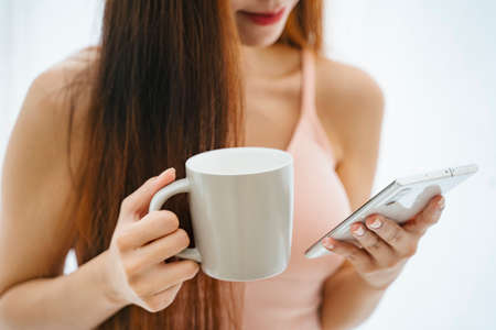 Beautiful asian woman with a cup of coffee and smartphone.の写真素材
