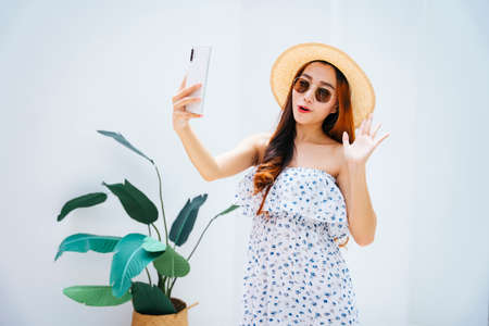 Beautiful asian traveler woman wearing sunglasses and hat vlogging or live stream with smartphone.の写真素材