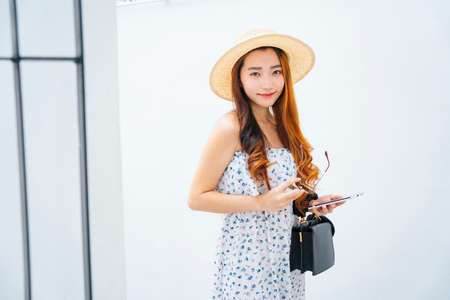 Beautiful asian traveler woman wearing hat holding sunglasses isolate on white background.の写真素材