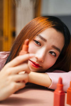 Beautiful young asian woman looking at lipstick.の写真素材
