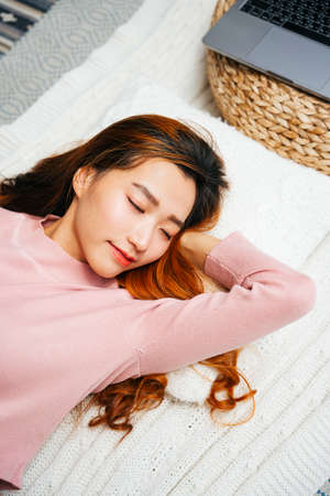 Top view - Beautiful young asian woman wearing pink sweater sleeping on pillow. Autumn vibe.の写真素材