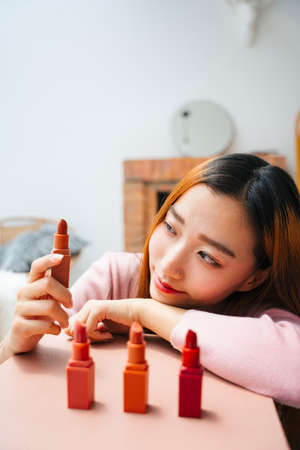 Beautiful young asian woman with many lipsticks on table.の写真素材