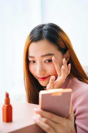 Beautiful asian woman doing make up and looking at portable mirror.の写真素材