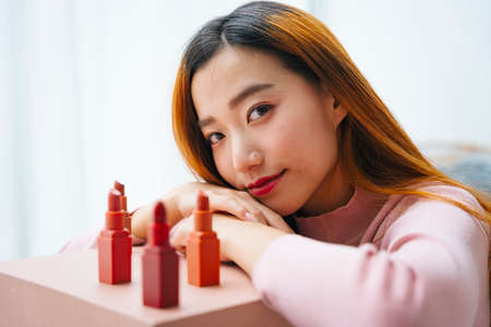 Beautiful young asian woman with many lipsticks on table.の写真素材