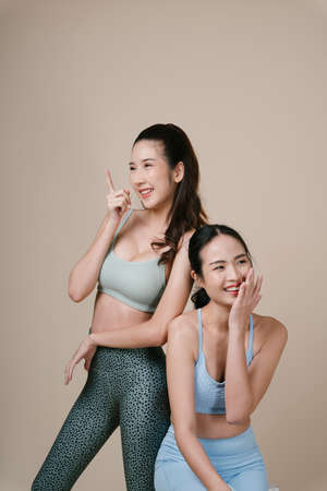 Portrait of two athlete asian sporty woman pointing finger at empty space.の写真素材