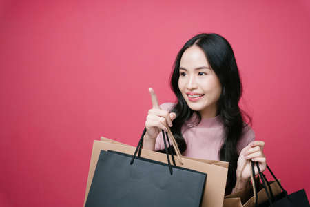 Shopping lover holding many shopping paper bags pointing finger at empty space.の写真素材