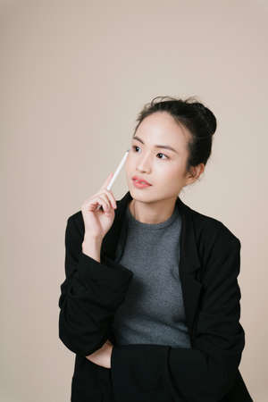 Portrait of asian business woman wear black jacket isolate on beige background.の写真素材