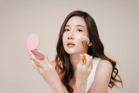 Portrait of beautiful young asian woman applying cosmetic powder on her face.の写真素材