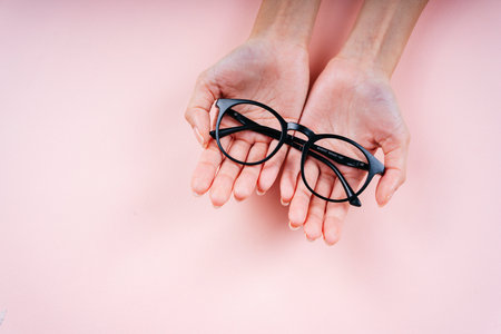 Hand of woman holding eyeglasses isolate on light pink background.の写真素材