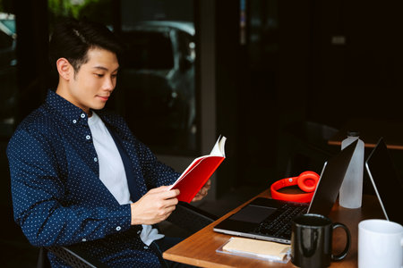 Young asian businessman reading a book before get back to work.の写真素材