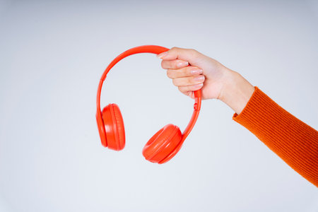 Woman hands holding red headphones isolate on white background.