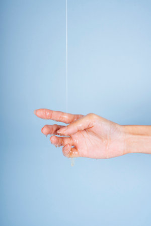Woman hand with liquid oil lotion cream pouring from above.の写真素材