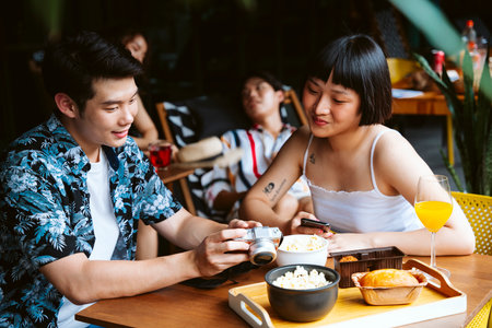Asian couple looking at picture in camera. People on summer trip with friends.の写真素材