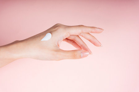Woman hand applying lotion cream isolate on pink background.の写真素材