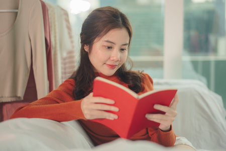 Beauty young asian woman black hair reading red book at home.の写真素材