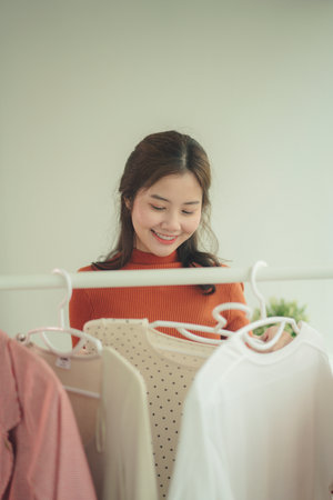 Beauty young asian woman black hair selecting clothes from rack at home.の写真素材