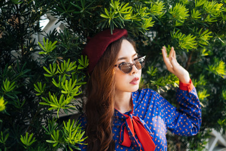 Wavy brunette woman in blue and red retro dress and sunglasses standing in the bush.の写真素材