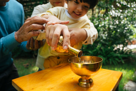 Asian family pouring water from golden grail after gave alms offering to monk.の写真素材