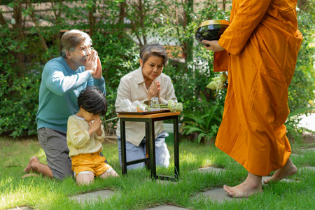 Asian family pay respect to monk after giving alms offering.の写真素材