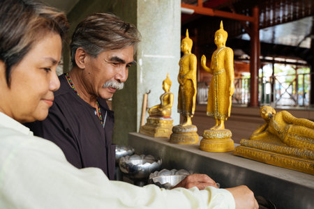 Asian senior elderly old couple praying to buddha statue in temple.の写真素材
