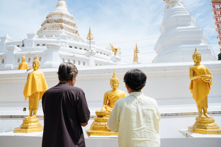 Back view - Asian senior elderly old couple pay respect to buddha statue in thai temple.の写真素材