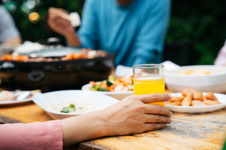 Hand of woman holding orange juice glass in dining party outdoor.の写真素材