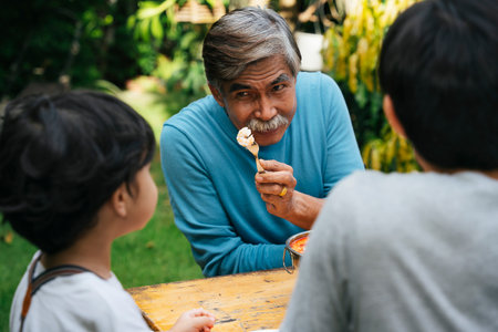 Grandfather giving boiled shrimp to son in dining party outdoors.の写真素材