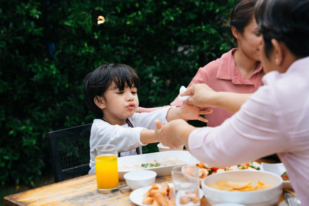 Asian kid and mother have dining outdoor at yard.の写真素材