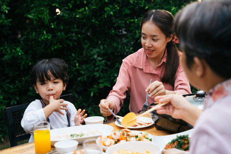 Asian kid and mother have dining outdoor at yard.の写真素材