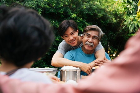Happy father and son having good time enjoy dining outdoors at yard.