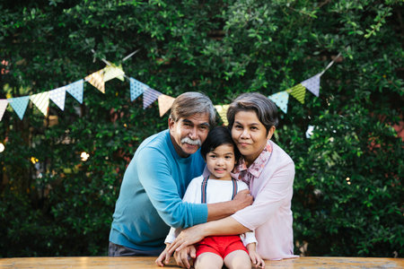 Portrait of asian family with son, grandfather, grandmother hugging outdoors at yard.の写真素材