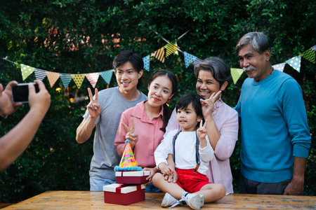 Asian family portrait taking photo with smartphone in birthday celebration party outdoor.の写真素材