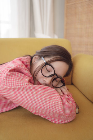 Close up portrait young asian beauty woman wear eyeglasses sleeping on a couch.の写真素材