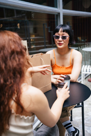 Portrait of young asian women wear sunglasses talking with her friend at cafe.の写真素材