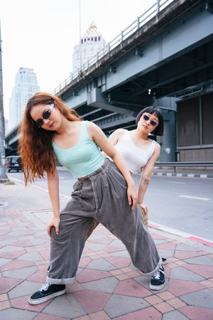 Portrait of two hipster young asian women wearing sunglasses on street.の写真素材
