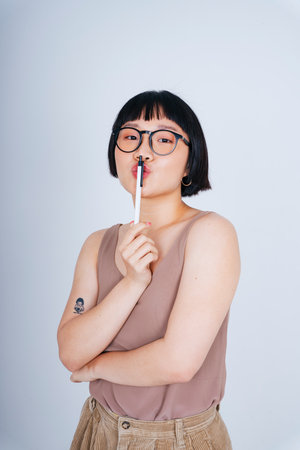 Portrait of young asian woman short bob hairstyle wearing sunglasses holding pen isolate on white background.の写真素材