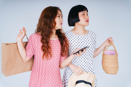 Portrait of two young asian women enjoy online shopping on smartphone application isolate on white background.の写真素材