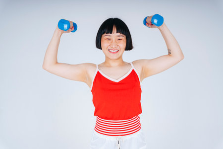 Young asian woman wearing red shirt holding dumbbells isolate on white background.の写真素材