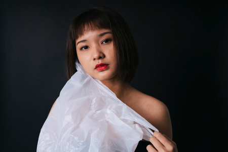 Beautiful asian thai woman short hair with plastic bag isolate over black background. Close up...