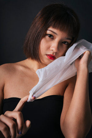 Plastic fashion concept. Beautiful asian thai woman short hair with plastic bag isolate over black background.の写真素材
