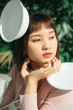 Plastic waste concept. Close up - asian thai woman short hair with plastic waste accessorise over green background.の写真素材