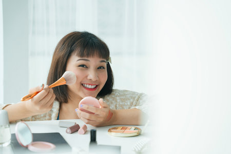 Beautiful pretty young asian thai woman enjoy using cosmetic brush tools in white room.の写真素材