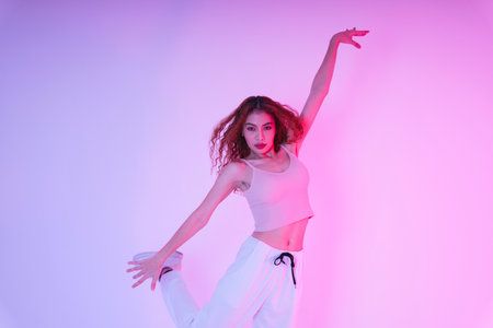 Active young asian curly hair girl dancing in neon light at studio indoors.