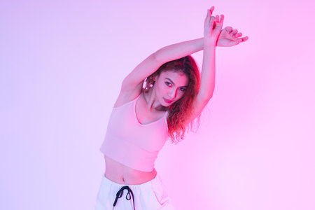 Active young asian curly hair girl dancing in neon light at studio indoors.