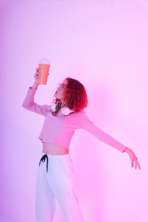 Portrait of young asian woman curly hairstyle wearing eyeglasses and handphone holding beverage cup.の写真素材