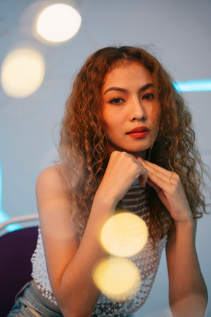 Fashion portrait of young asian curly hair woman with yellow bokeh in modern room.の写真素材
